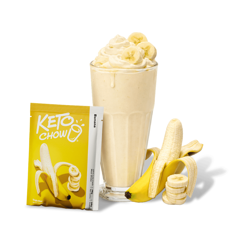 KETO CHOW Banana Ultra Low-Carb Meal Shake mix yellow pouch, with prepared shake in glass, whipped cream, and fresh bananas.